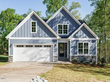 Charming blue home featuring stone accents, an attached garage, and a well-manicured lawn at 113 Tower Ridge Ln, Sanford, NC 27330