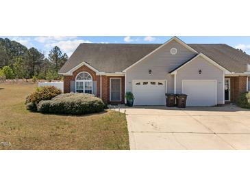 Charming home featuring a brick facade, grey siding, well-kept landscaping, and a two-car garage at 123 Ariel St, Lillington, NC 27546