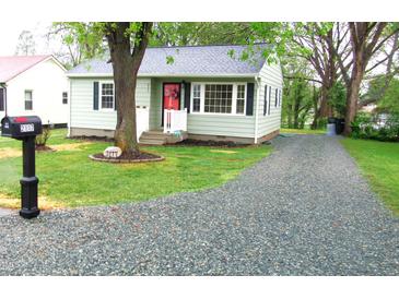 Charming single-story home features a gravel driveway, manicured lawn, and a cozy front porch with a red door at 2117 Wrenn St, Burlington, NC 27215