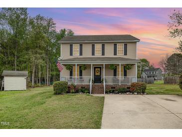 Charming home featuring a cozy front porch, well-maintained landscaping, and a welcoming American flag at 34 Stuart Dr, Benson, NC 27504
