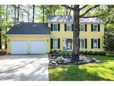 Charming yellow two-story home featuring a two-car garage and a beautifully landscaped front yard at 3900 Inkberry Ct, Apex, NC 27539