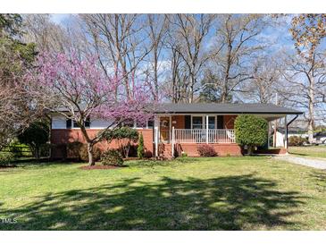 Charming brick home featuring a cozy front porch and a lovely flowering tree in the front yard at 5033 Green Oak Dr, Durham, NC 27712