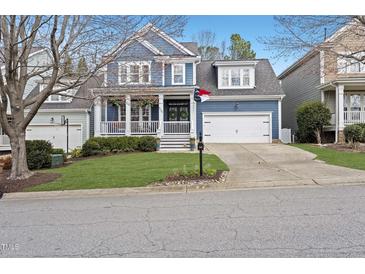 Charming two-story blue home with a welcoming front porch and well-manicured lawn at 504 Skygrove Dr, Holly Springs, NC 27540