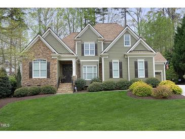 Charming two-story home with a well-manicured lawn, stone accents, and mature trees creating a picturesque setting at 515 Bexley Bluff Ln, Cary, NC 27513