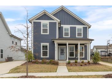 Charming two-story home with a covered front porch, blue siding, white trim, and well-maintained landscaping at 5712 Agrinio Way, Raleigh, NC 27603