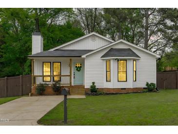 Charming white cottage-style home featuring a cozy porch and well-manicured lawn at 120 Cabrita Ct, Holly Springs, NC 27540