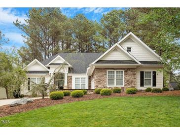 Charming home with a stone facade, manicured lawn and mature trees at 1537 Heritage Club Ave, Wake Forest, NC 27587