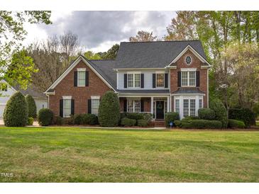 Charming two-story brick and siding home with a well-manicured lawn and mature landscaping at 2404 Gillingham Dr, Apex, NC 27539