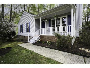 Charming home featuring a welcoming front porch with white railings and blooming flowers at 300 Round About Rd, Holly Springs, NC 27540