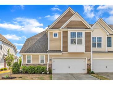 Inviting townhouse featuring a two-car garage and neutral colored siding against a bright blue sky at 318 Acorn Hollow Pl, Durham, NC 27703