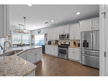 Well-lit kitchen featuring white cabinets, stainless steel appliances, and a dining area at 405 Club Center Dr, Youngsville, NC 27596