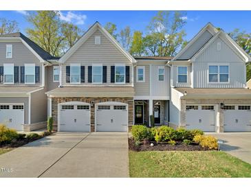 Charming townhome featuring stone accents, a two-car garage, and manicured landscaping at 425 Summit Trail Dr, Hillsborough, NC 27278