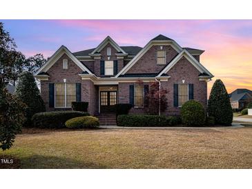 Stunning brick home boasts mature landscaping and a classic architectural design under a beautiful sunset sky at 502 Sippihaw Oaks Dr, Fuquay Varina, NC 27526