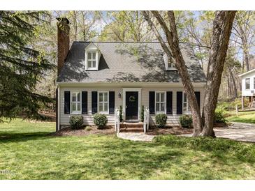Charming two-story home features a brick chimney, dormer windows, and landscaped yard with fresh green grass at 520 Tall Oaks Dr, Durham, NC 27713