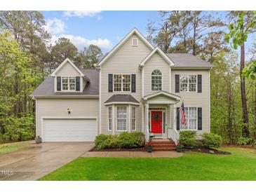 Charming two-story home featuring a bright red front door, well-manicured lawn, and attached two-car garage at 5405 Whisperwood Dr, Durham, NC 27713