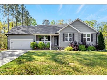 Charming single-story home features a well-maintained lawn, attached garage, and inviting front porch at 55 Northdale Ct, Louisburg, NC 27549