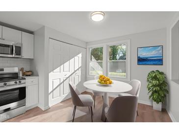 Bright eat-in kitchen with stainless steel appliances, white cabinets, and access to closet storage at 7715 Bernadette Ln, Raleigh, NC 27615