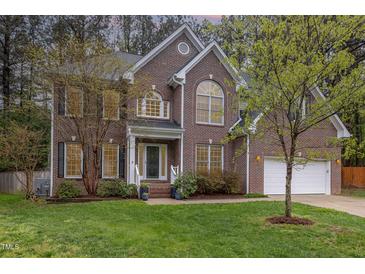 Beautiful two-story brick home with a manicured lawn, attached garage, and lush trees at 8 Queensland Ct, Durham, NC 27712