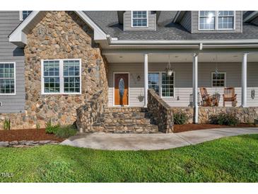 Charming front entrance featuring stone accents, wood door, and rocking chairs on the inviting front porch at 9026 Privette Hill Ln, Spring Hope, NC 27882