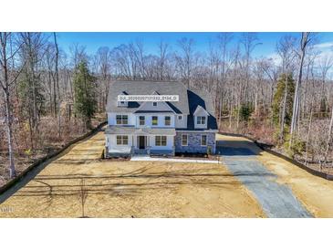 New construction home with stone accents and covered entry surrounded by wooded acreage at 0006 Tallulah Loop Lane, Cedar Grove, NC 27231
