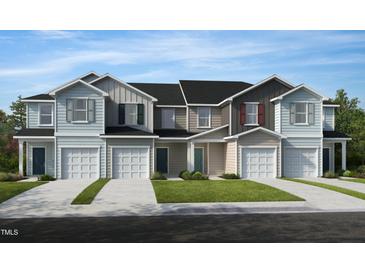 Charming townhomes showcasing varied siding colors and attached garages against a bright blue sky at 152 Parker Ln, Mebane, NC 27302