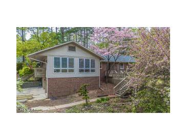 Charming home featuring a brick foundation and a bright sunroom surrounded by lush landscaping and flowering trees at 1705 Lord Ashley Dr, Sanford, NC 27330