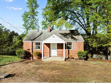 Charming brick home featuring a cozy front porch and mature trees at 203 W Pilot St, Durham, NC 27707