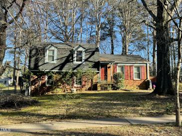 Charming brick home with red shutters and dormer windows nestled among mature trees at 2417 Lawrence Dr, Raleigh, NC 27603