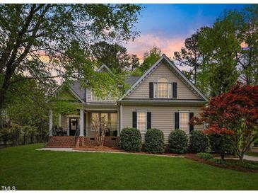 Charming home with manicured lawn, mature trees, and inviting front porch showcasing classic architectural details at 341 Heather Bluffs Dr, Garner, NC 27529