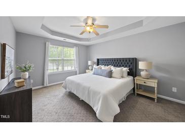 A spacious main bedroom features a tray ceiling with a ceiling fan and comfortable bedding at 4210 Brynwood Ave, Durham, NC 27713
