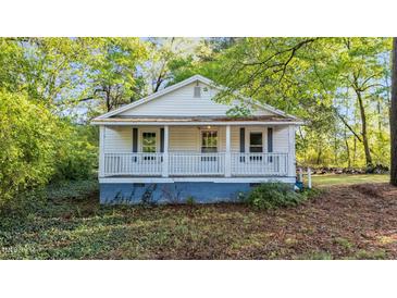 Charming home featuring a cozy front porch with white railings and blue accents, surrounded by lush greenery at 8175 Nc 27 E, Coats, NC 27521