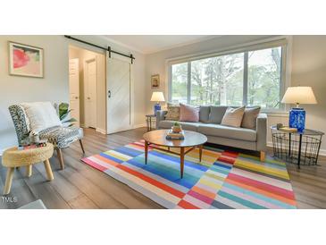 Bright living room with a large window, colorful rug, modern furniture and a sliding barn door at 116 Crawford Rd, Hillsborough, NC 27278