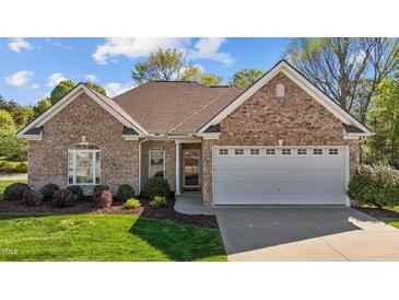 Charming brick home featuring a well-manicured lawn, arched window and attached two-car garage at 252 Shea Ct, Graham, NC 27253