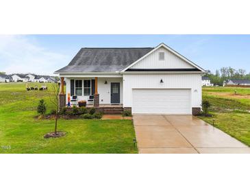 Charming single-Gathering home with a well-manicured lawn and a welcoming front porch with chairs at 295 Springtooth Dr, Zebulon, NC 27597