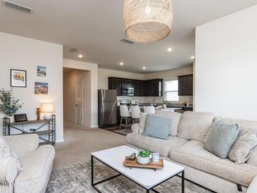 Inviting living room with modern furnishings flowing into kitchen with stainless steel appliances at 3521 Strawberry Patch Row, Raleigh, NC 27604