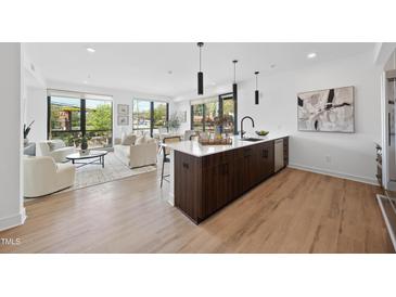 Open concept kitchen with wood floors, island, stainless steel appliances, pendant lights, and living space at 615 W Peace St # 201, Raleigh, NC 27605