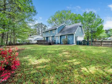 Spacious backyard featuring a well-maintained lawn, wooden fence, and charming blue house with a deck at 6216 Valley Estates Dr, Raleigh, NC 27612