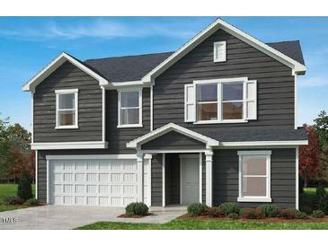 Charming two-story home with a front-facing two-car garage and professionally landscaped yard at 86 Orchard St, Lillington, NC 27546