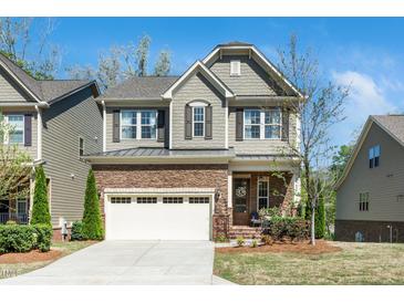 Charming two-story home featuring a stone and siding exterior with a two-car garage and manicured lawn at 936 Regency Cottage Pl, Cary, NC 27518