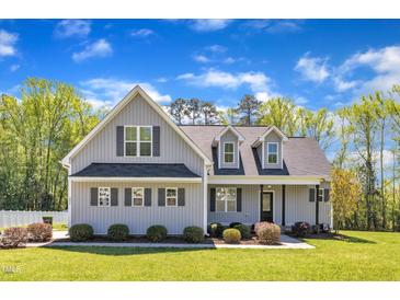 Charming two-story home with gray siding, a black roof, and well-manicured landscaping at 1077 Williams-White Rd, Zebulon, NC 27597