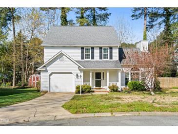 Charming two-story home with a well-manicured lawn, attached garage, and inviting front porch at 12325 Inglehurst Dr, Raleigh, NC 27613