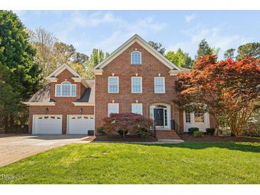 Beautiful two-story brick home with a well-manicured lawn and lush landscaping, including colorful trees at 125 Kelekent Ln, Cary, NC 27518