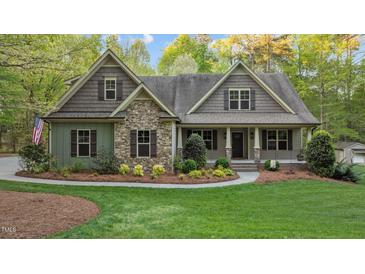 Charming home featuring stone accents, landscaped yard, covered porch and meticulous landscaping at 2204 Secluded Oaks Ct, Wake Forest, NC 27587