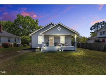 Charming home with a cozy front porch, swing, and chairs, all beautifully illuminated at twilight at 303 E J St, Erwin, NC 28339