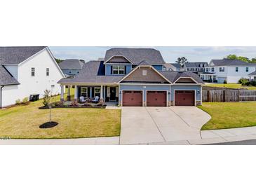Charming home featuring a three-car garage, landscaped yard, and cozy front porch with seating at 34 Tea Olive Ct, Clayton, NC 27520