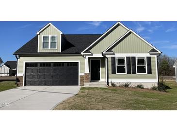 Charming home featuring sage vinyl siding, a black garage door, and tasteful stone accents at 37 Heatherglenn Cir, Princeton, NC 27569