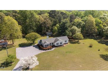 Expansive aerial view of home with manicured lawn, mature trees, and a cozy wraparound deck, perfect for outdoor living at 413 Bayles Rd, Lillington, NC 27546