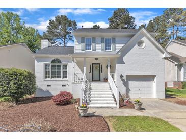 Charming two-story home features a white painted brick exterior, gabled roof, and manicured front yard at 8721 Attingham Dr, Raleigh, NC 27615