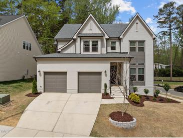 Beautiful two-story home featuring a white painted brick exterior, a two-car garage, and manicured landscaping at 127 Sanderway Dr, Chapel Hill, NC 27516