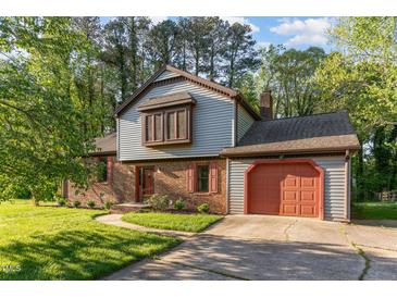 Charming home with a brick and siding exterior, featuring a well-manicured lawn and mature trees at 1400 Rainwood Ln, Raleigh, NC 27615